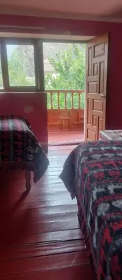 a bedroom with a bed and a porch with a window at Hospedaje La Ñusta in Ollantaytambo