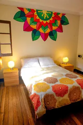a bedroom with a bed with a painting on the wall at Bear Packer Hostel in Cusco