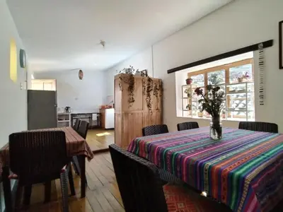 a dining room with a table with a vase on it at El Jardín de Jeni in Cusco