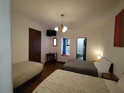 a living room with two beds and a television at El Jardín de Jeni in Cusco