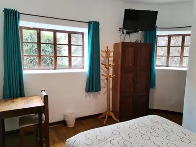 a bedroom with blue curtains and a bed and a television at El Jardín de Jeni in Cusco