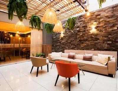 a lobby with a couch and chairs and a stone wall at Hotel El Tambo 2 in Lima