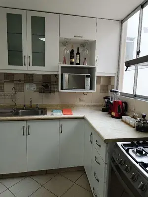 a kitchen with white cabinets and a sink and a stove at Runawasi Apartments - Amaru 3BDR in Lima