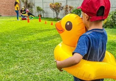 a young boy holding a yellow rubber duck balloon at KUSI WASI CIENEGUILLA in Cieneguilla