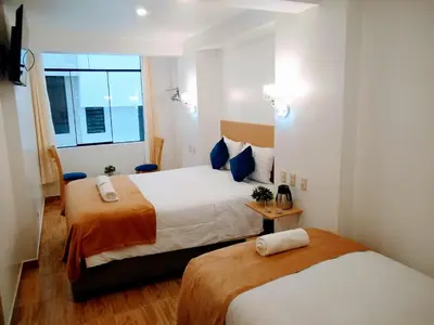 a hotel room with two beds and a window at Emmanuel inn Machupicchu in Machu Picchu