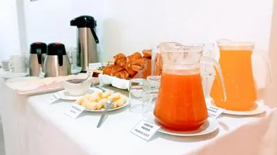 a table with two pitchers of orange juice and snacks at Emmanuel inn Machupicchu in Machu Picchu