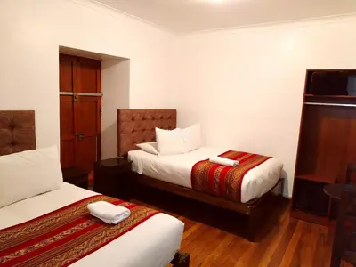 a hotel room with two beds and a tv at Paqarina San Blas in Cusco