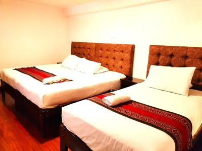 two beds in a hotel room with white sheets at Paqarina San Blas in Cusco