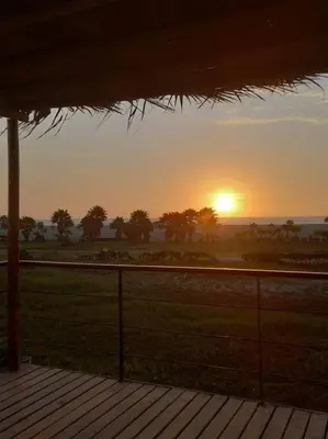 a sunset over a field with a fence and trees at The Pacific Cottage in Chincha Baja