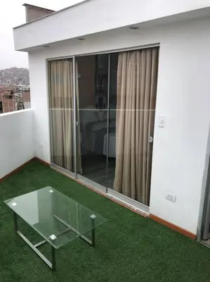 a balcony with a glass table and green grass at Hermoso Duplex en Chorrillos in Lima