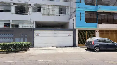 a car parked in front of a building with two garage doors at Hermoso departamento amoblado con piscina, area parrillas in Lima