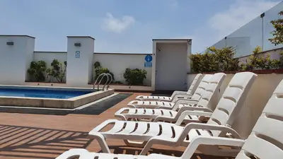 a row of white chairs sitting next to a pool at Hermoso departamento amoblado con piscina, area parrillas in Lima
