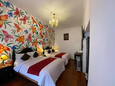 a bedroom with two beds and a floral wallpaper at Casona Dorada Hotel Cusco in Cusco