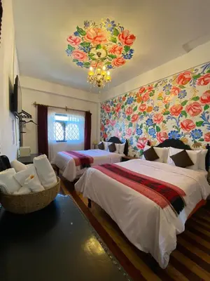 a bedroom with two beds and a floral wall at Casona Dorada Hotel Cusco in Cusco