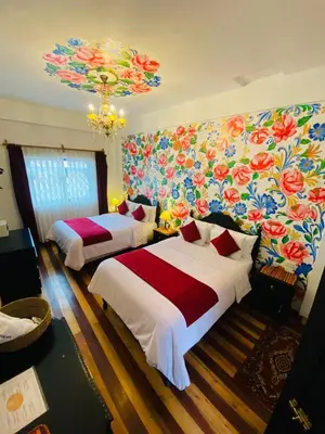 a bedroom with two beds and a floral wall at Casona Dorada Hotel Cusco in Cusco