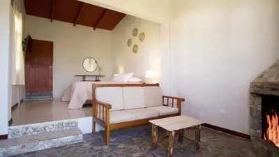 a living room with a bed and a couch and a fireplace at Tuki Llajta - Pueblo bonito Lodge in Huancayo