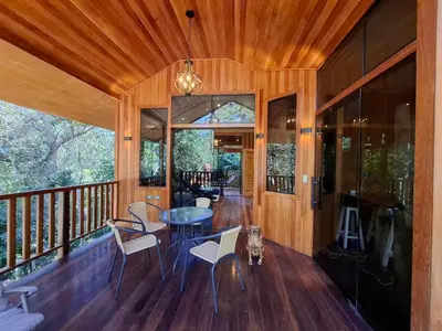a room with a table and chairs on a balcony at La casa del Erizo in Oxapampa