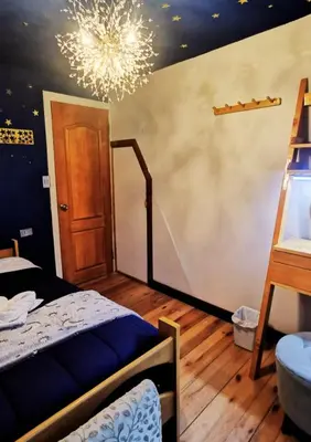 a bedroom with a bed and a chandelier at La casa del Erizo in Oxapampa