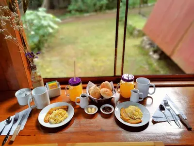 a table with plates of breakfast food and orange juice at La casa del Erizo in Oxapampa