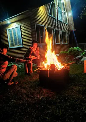 a group of people sitting around a fire in front of a house at La casa del Erizo in Oxapampa