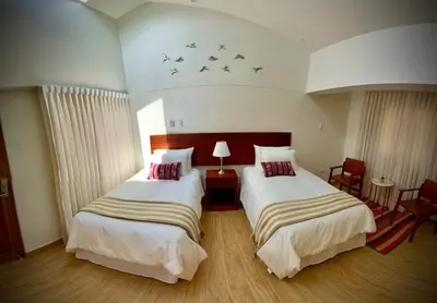 two beds in a hotel room with birds on the ceiling at Inkantari Boutique Hotel in Cusco