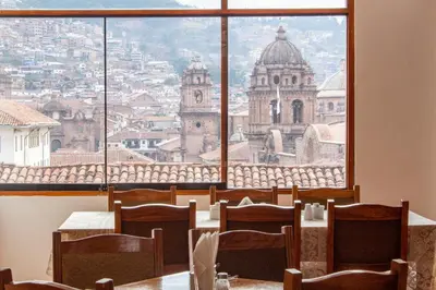 a room with a table and chairs and a large window at Hotel Amerinka in Cusco