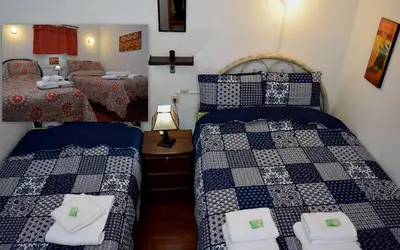 a bedroom with two beds and a table with a lamp at Carlos Guest House 2 Cusco in Cusco