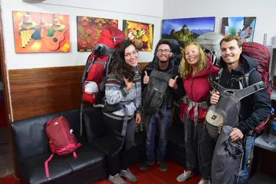a group of people standing next to a couch with backpacks at Carlos Guest House 1 Cusco in Cusco