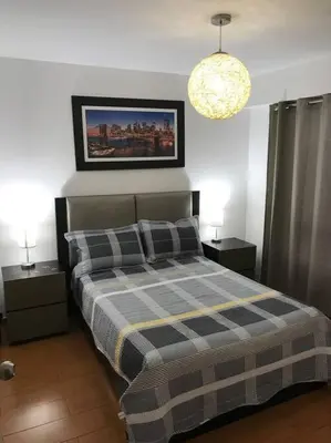 a bedroom with a bed with a checkered blanket and two night stands at Lindo Departamento en Av. Guardia Civil 861 - Chorrillos in Lima