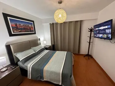 a bedroom with a bed and a tv on the wall at Lindo Departamento en Av. Guardia Civil 861 - Chorrillos in Lima