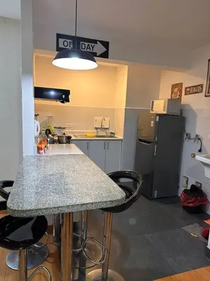 a kitchen with a counter with stools and a refrigerator at Lindo Departamento en Av. Guardia Civil 861 - Chorrillos in Lima