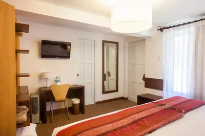 a bedroom with a bed and a desk and a mirror at Tierra Viva Cusco San Blas in Cusco
