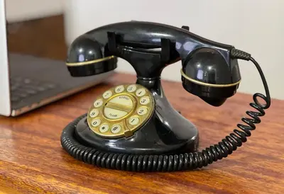 a black phone sitting on a wooden desk at QUECHUA´S HOUSE Hostal & Coffee in Machu Picchu