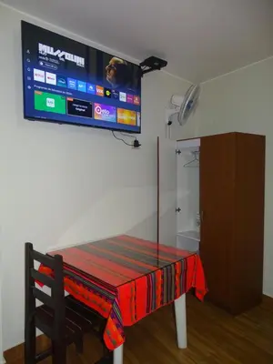 a room with a table with a tv on the wall at Hospedaje Dimar Inn in Lima