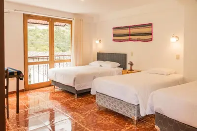 two beds in a room with a balcony at Sueños del Valle Sagrado in Urubamba
