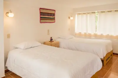 two beds in a room with white walls at Sueños del Valle Sagrado in Urubamba