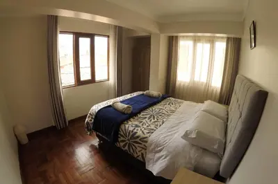a bedroom with a bed and two windows at Centric & cozy apartment with Garage in Cusco