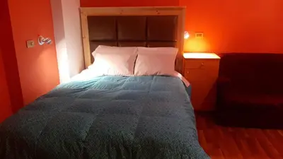 a bedroom with a bed with an orange wall at BROTHERs HOUSE II in Cusco