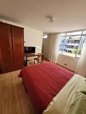 a bedroom with a bed and a desk and a window at Habitación con baño propio para 2 personas como máximo in Lima