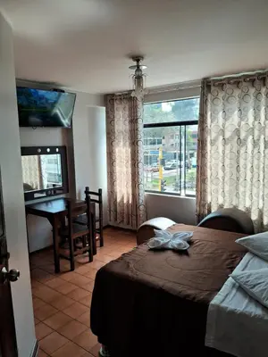 a bedroom with a bed and a desk and a window at LAS ARTES INN in Lima