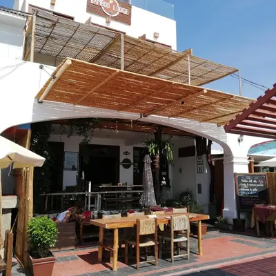 a patio with a wooden table and chairs under awning at Bamboo Lodge Paracas in Paracas