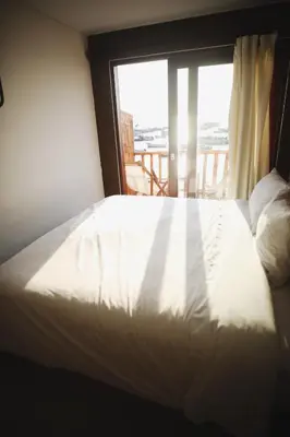 a bedroom with a white bed and a window at Bamboo Lodge Paracas in Paracas