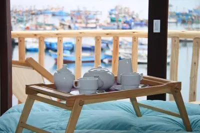 a tray with cups and tea sets on a bed at Bamboo Lodge Paracas in Paracas