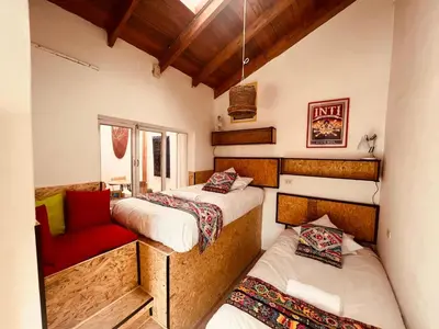 a room with two beds and a red chair at Saqray Hostel in Cusco