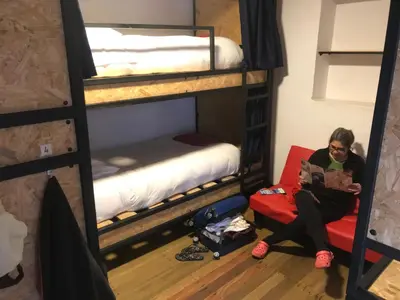a woman sitting on a couch in a room with bunk beds at Saqray Hostel in Cusco