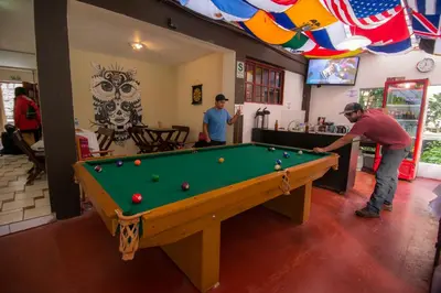 two men playing pool in a room with a pool table at Casa Machu Picchu Hostel in Machu Picchu
