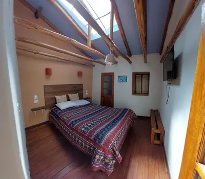 a bedroom with a large bed in a room with wooden floors at Mirador de la Ñusta in Cusco