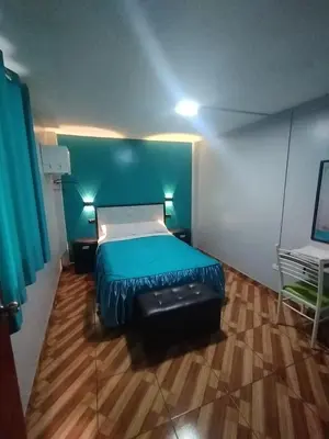 a bedroom with a bed and a suitcase in it at Hostal El Pilar in Lima