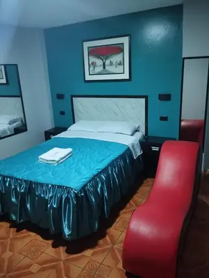 a bedroom with a bed and a red chair at Hostal El Pilar in Lima