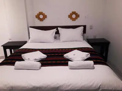 a bed with two pillows and towels on it at PAKARINA HOTEL in Machu Picchu